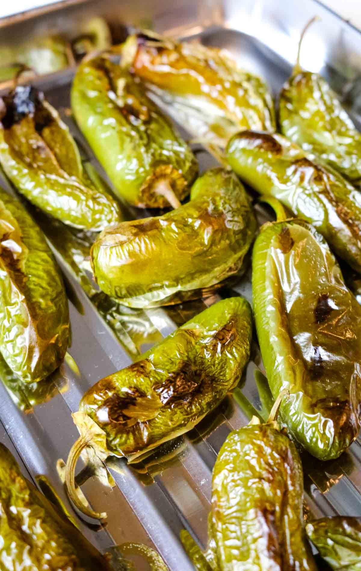 blistered and charred jalapeno peppers on a sheet.