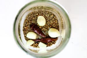 seasonings, fresh garlic and red chili pepper in a mason jar.