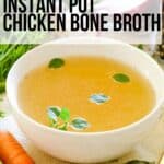 chicken broth in white bowl with carrots and bay leaves.