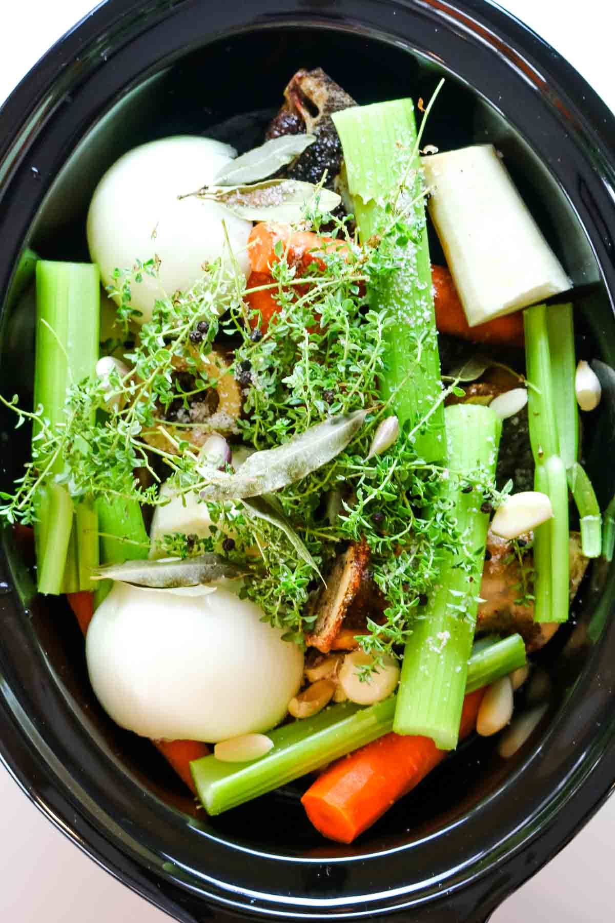 vegetables added to beef bone broth in slow cooker.