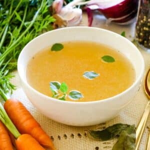 chicken bone broth in white mug with carrots.