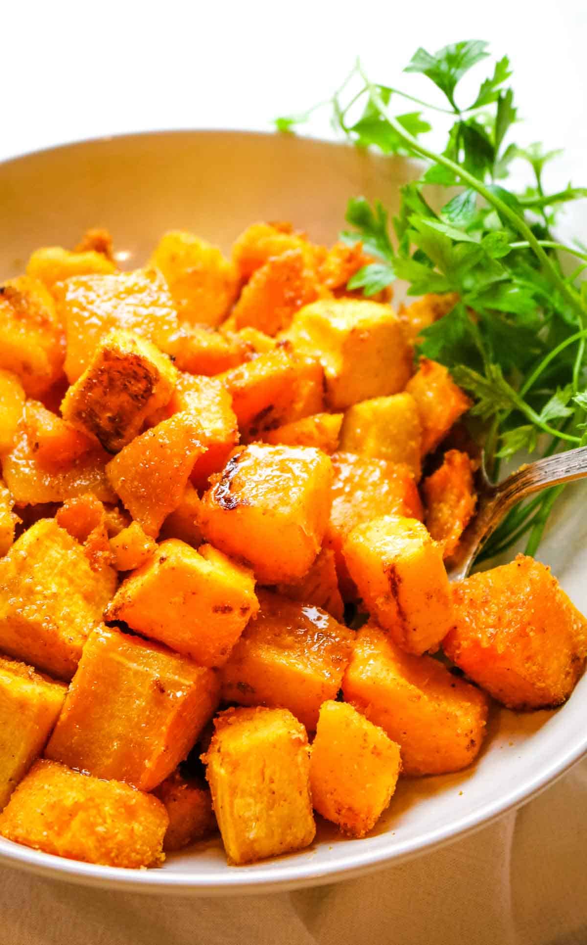 Butternut squash in white bowl with fresh parsley.