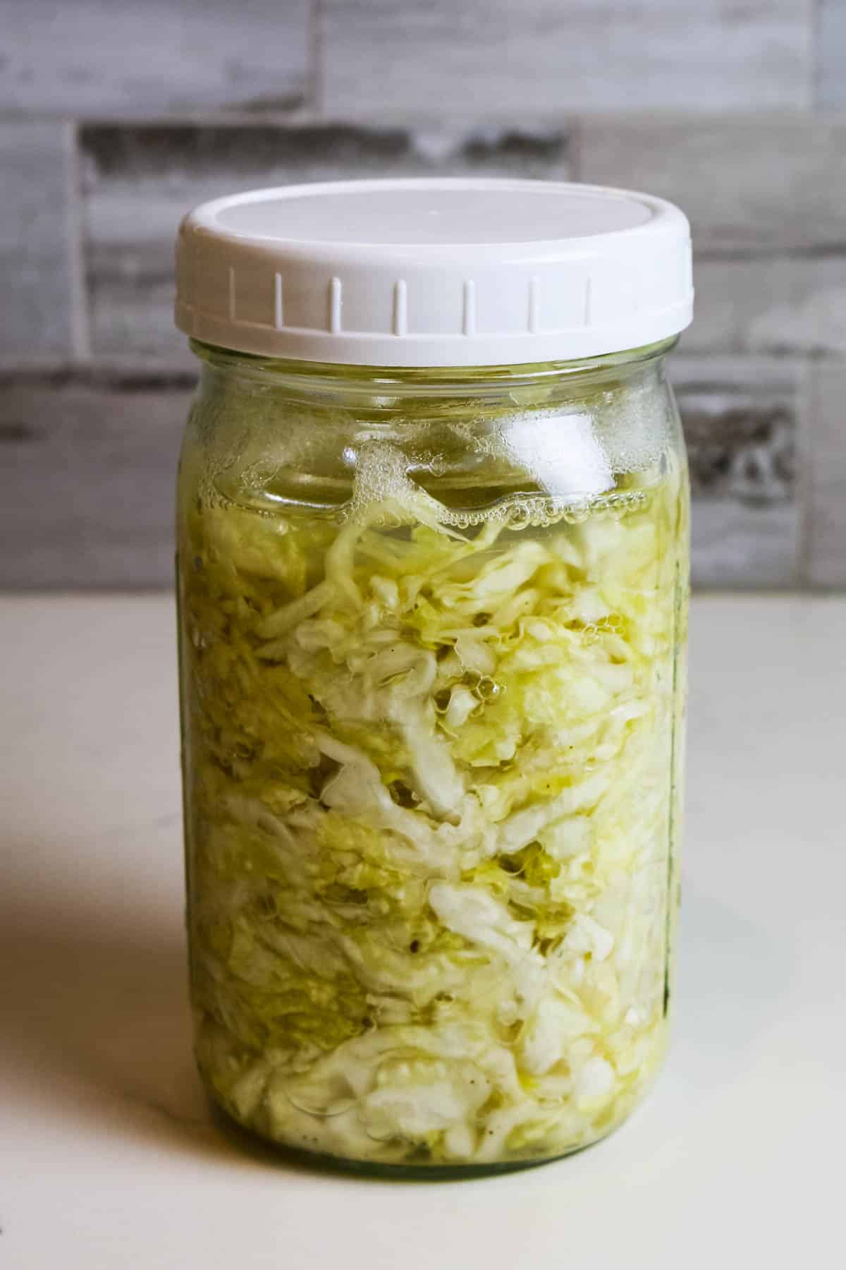 raw sauerkraut in mason jar with grey background.