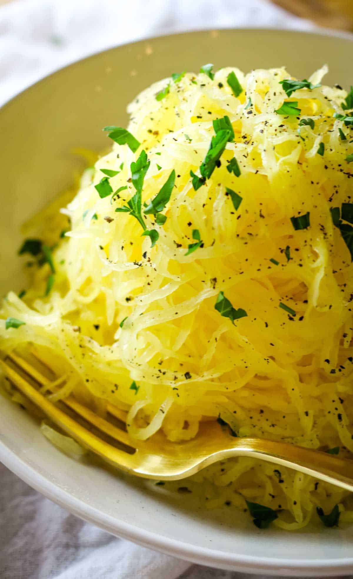 spaghetti squash with fresh parsley on a white bowl.