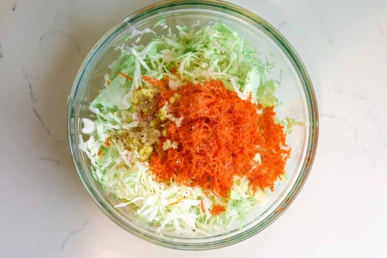 adding carrots, ginger, and garlic to cabbage.