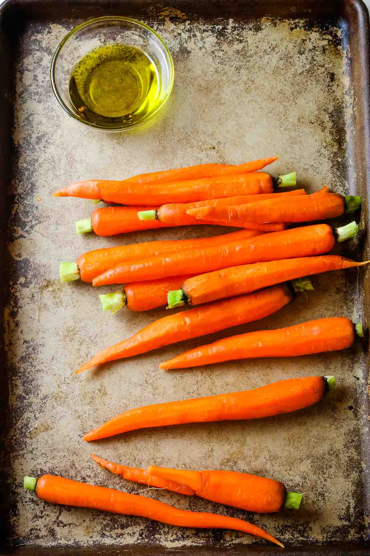 trimmed carrots on sheet with oil.