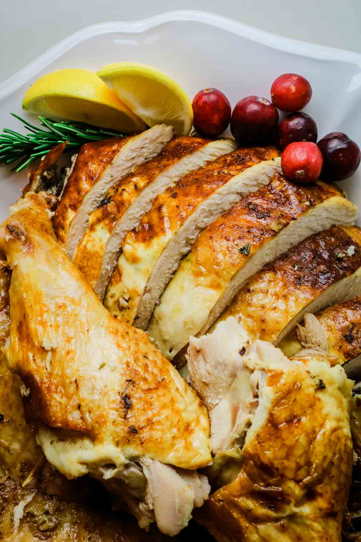 carved turkey with cranberries and lemon wedges.