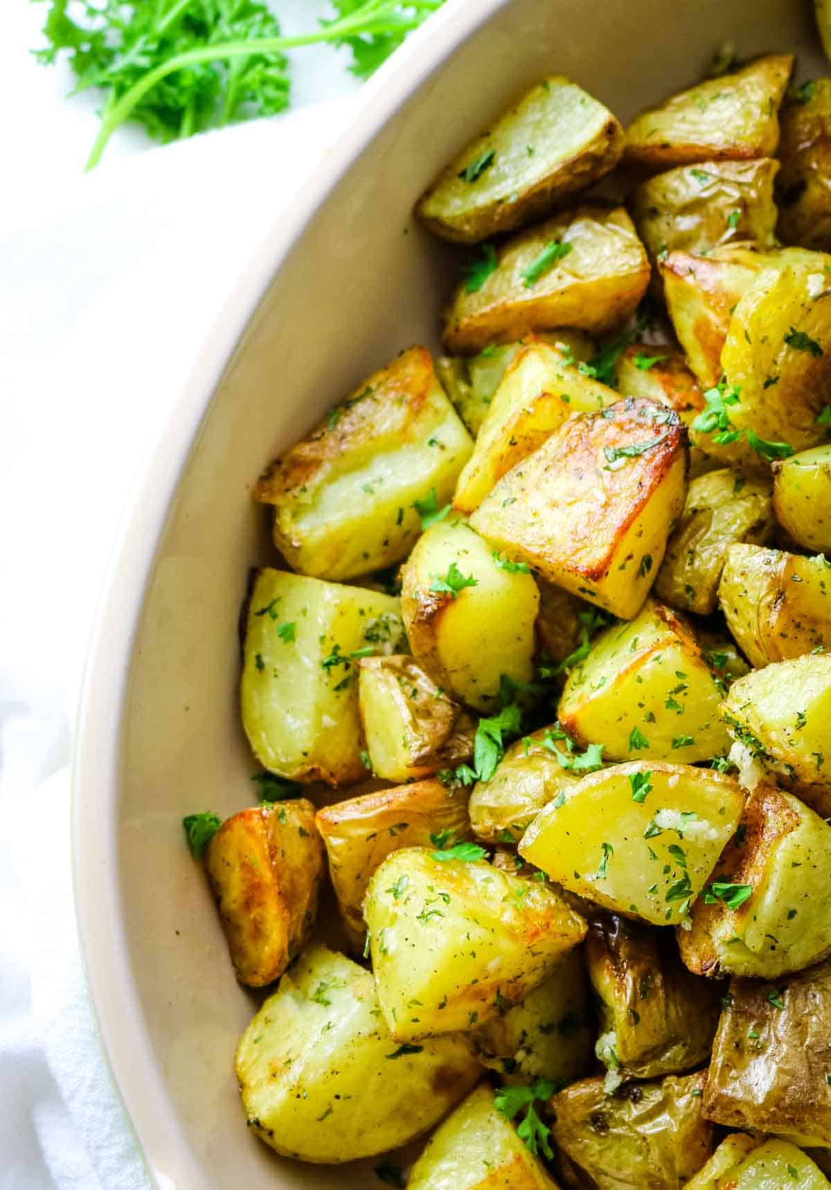 roasted potatoes with golden edges and garlic in platter