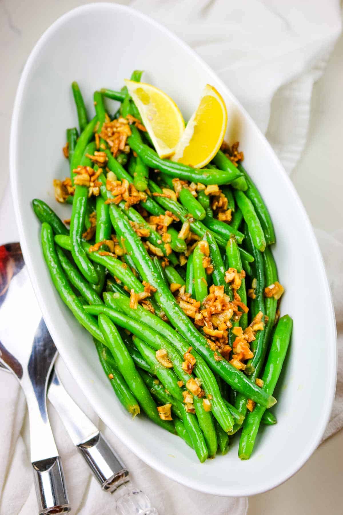 green beans with morsels of browned garlic and lemon wedges.