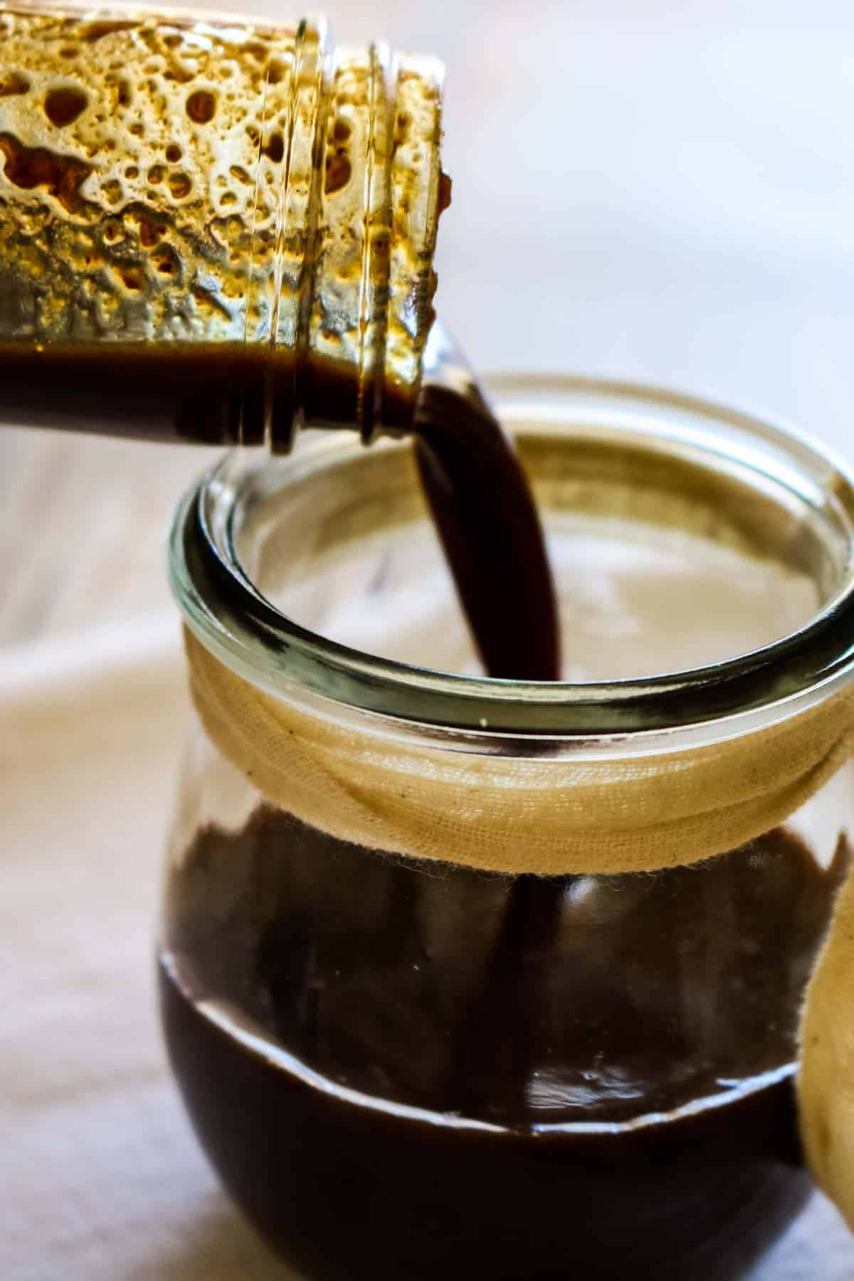 dark sauce being poured into a jar.