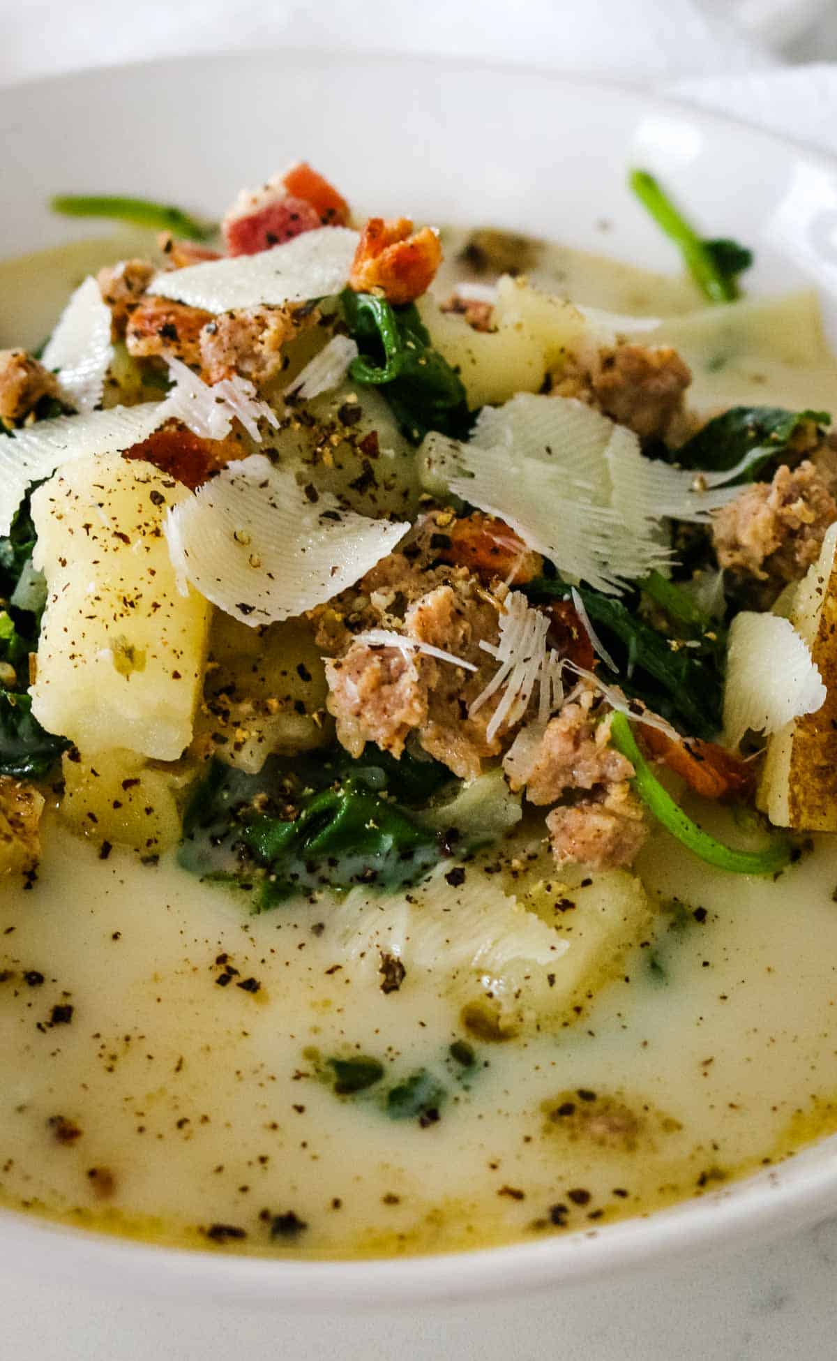 sauage, potatoes and parmesan in a bowl with creamy broth.