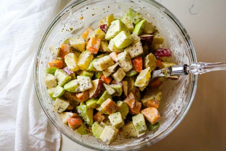 fall fruit salad mixed with yogurt dressing with spoon.