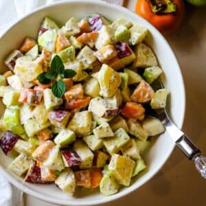 fall fruit salad in white bowl and serving spoon.