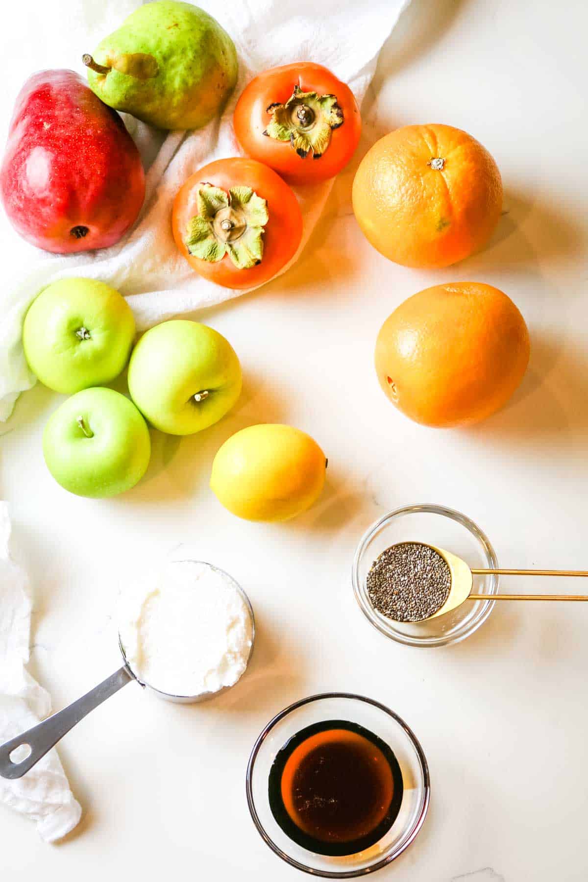 ingredients for fall fruit salad recipe like apples, persimmons, and pears. 