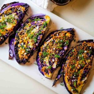 Roasted purple cabbage with dill and garlic on white platter.