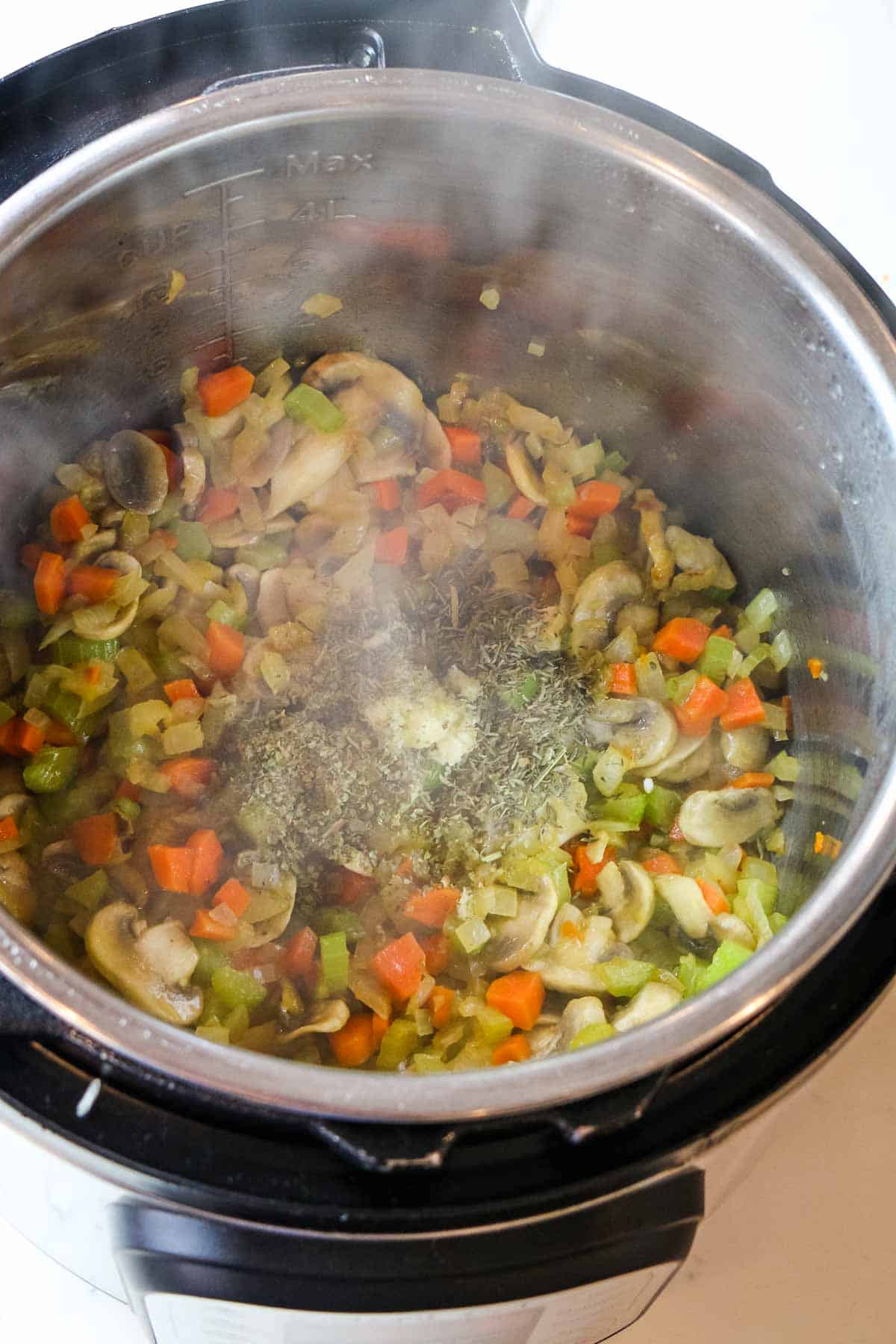 adding garlic and spices to instant pot veggies.