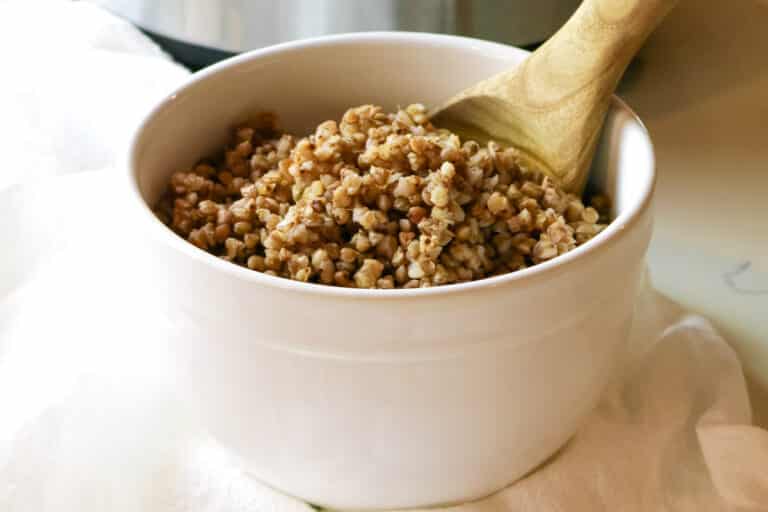 buckwheat in a white bowl with wooden spoon.