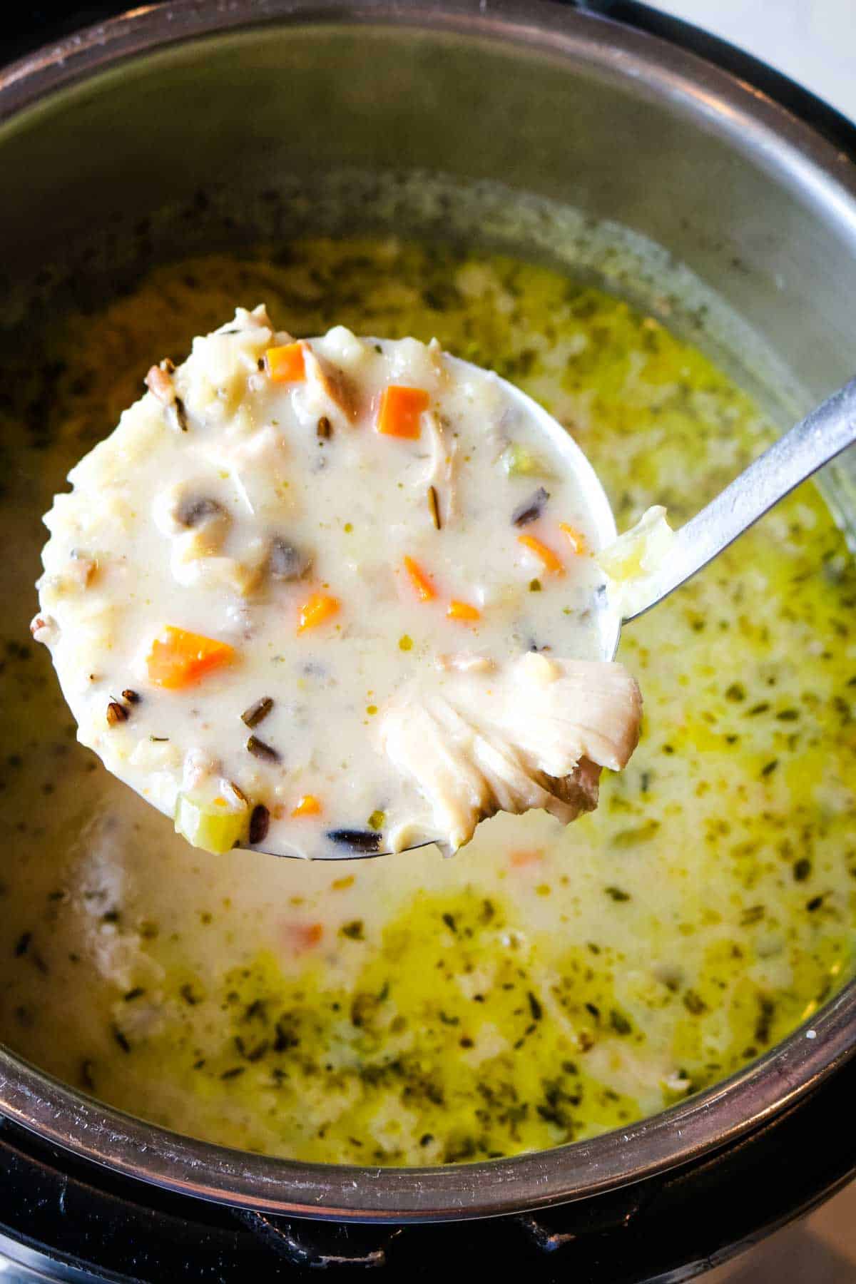 Chicken wild rice soup in ladle over instant pot.