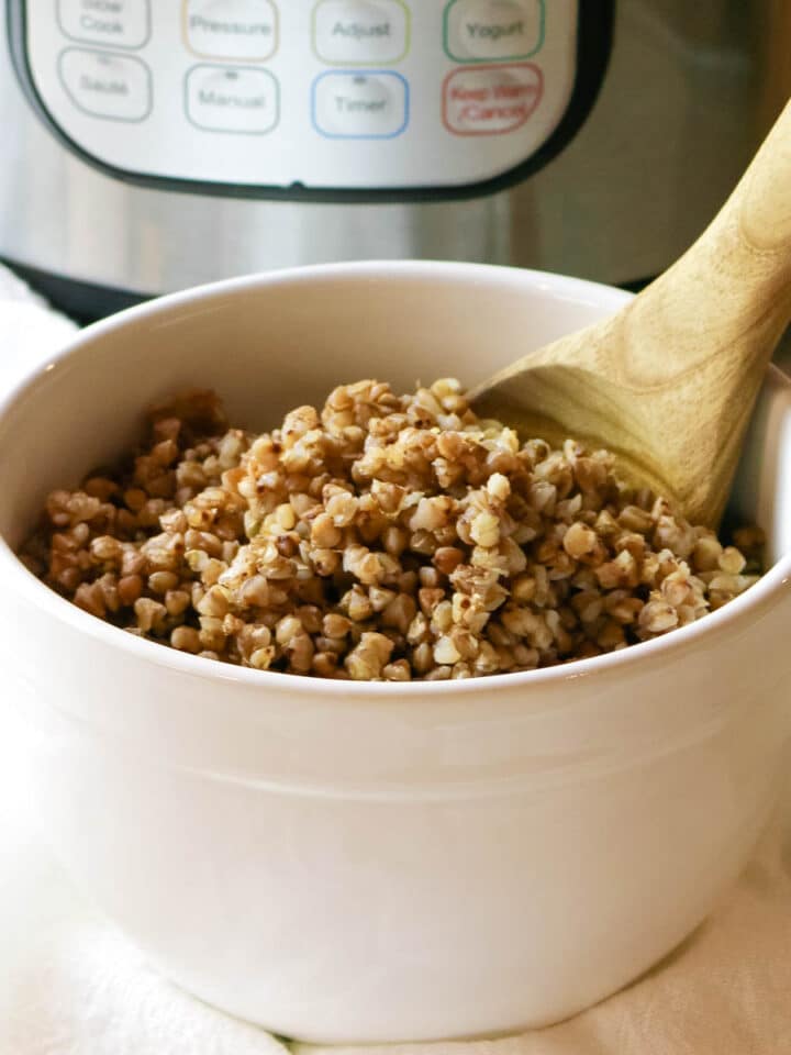 cooked buckwheat in a white bowl with Instant Pot in background