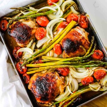 golden brown balsamic chicken roasted on sheet pan with asparagus, tomatoes, and onions.