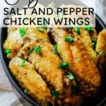 crispy salt and pepper chicken wings in black dish with text overlay.