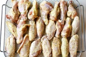Chicken wings on crisper tray spread out in single layer.