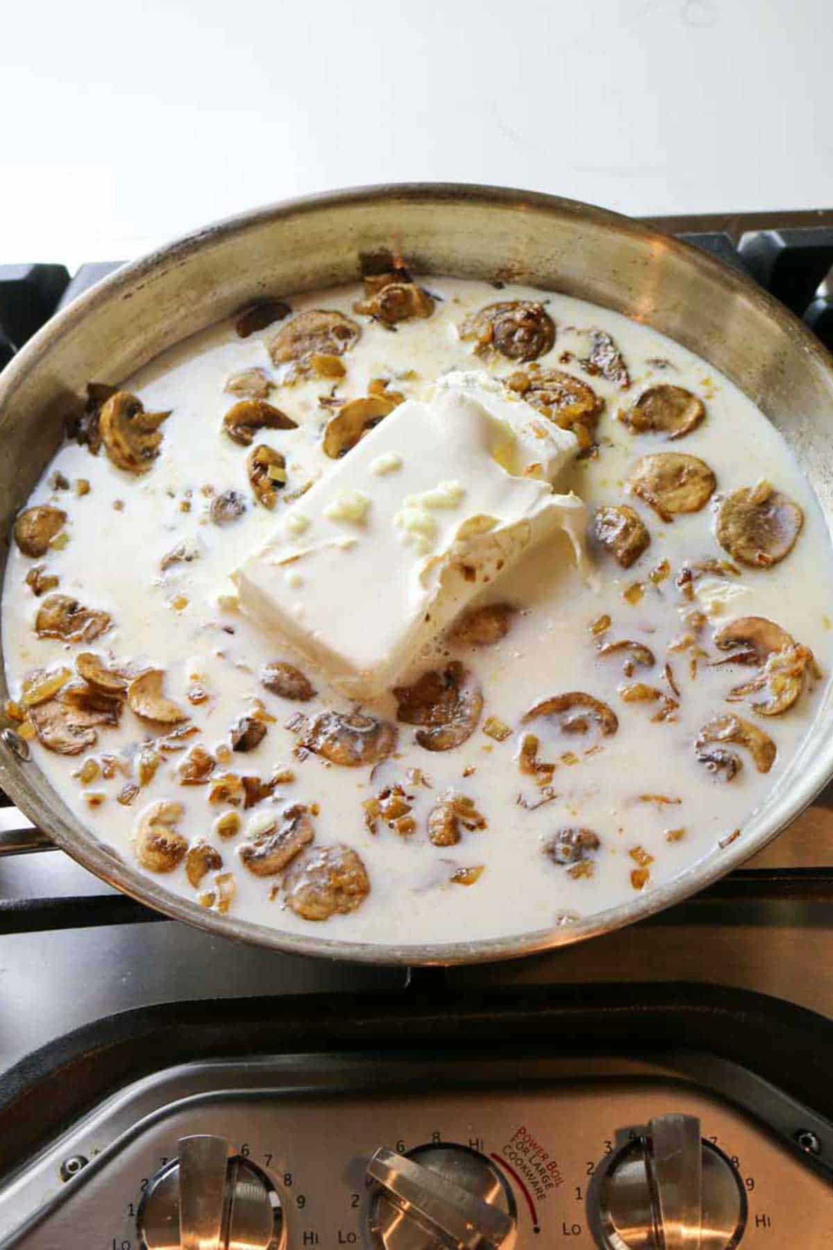 cream cheese block added to milky mushroom mixture in large skillet.