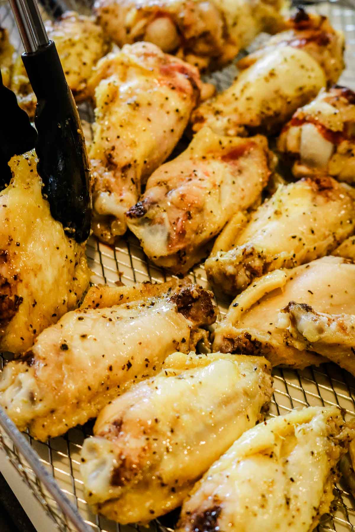 flipping the chicken wings with black tongs.