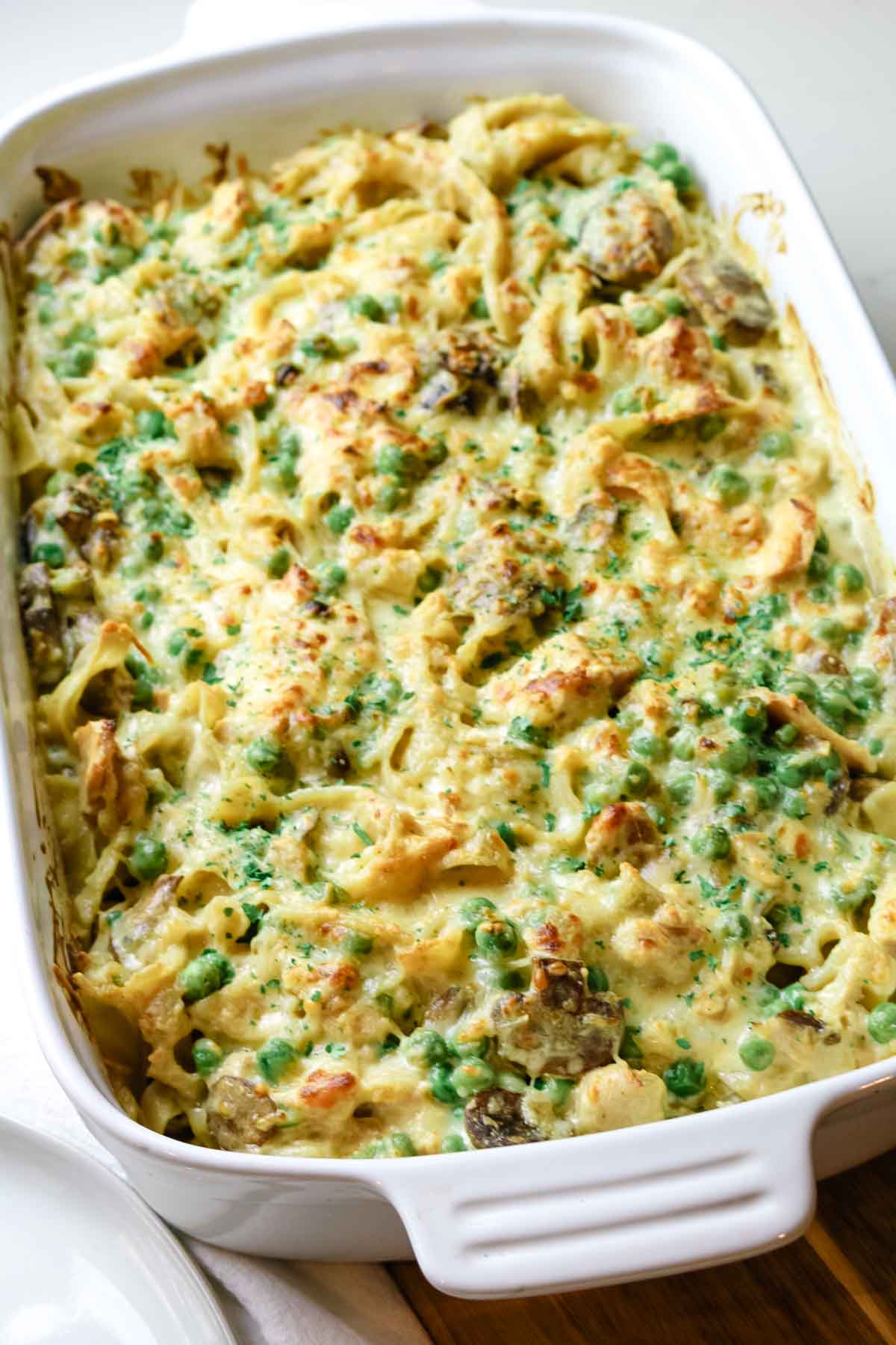 tuna casserole with noodles and peas in white casserole dish.
