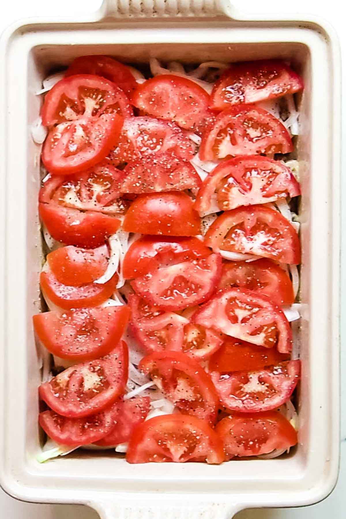 adding onions and tomatoes on top of chicken.