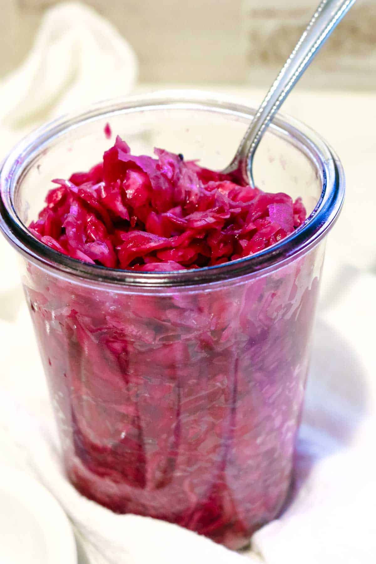 red cabbage fermented in a glass jar with a spoon.