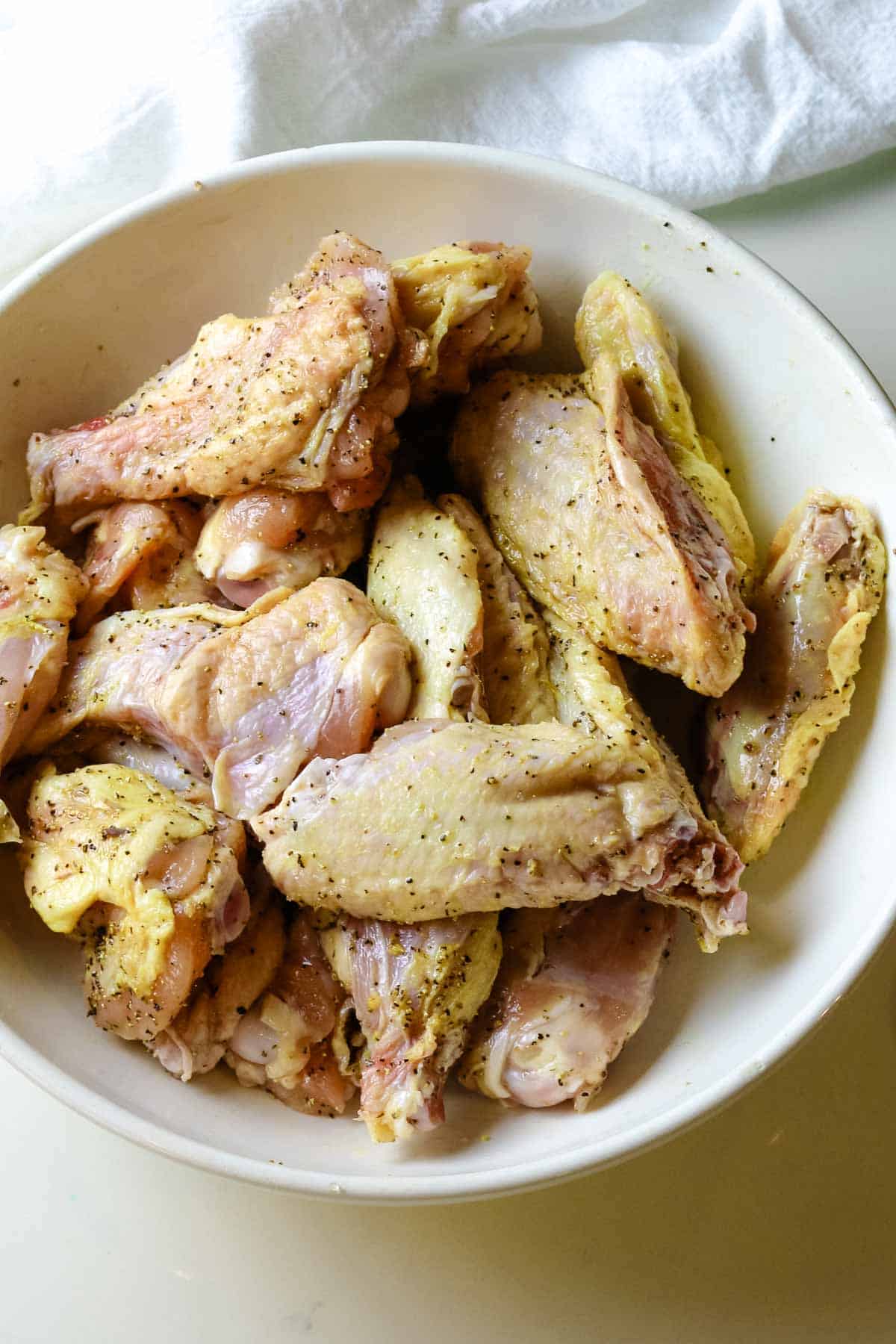 seasoned chicken wings in a white bowl.