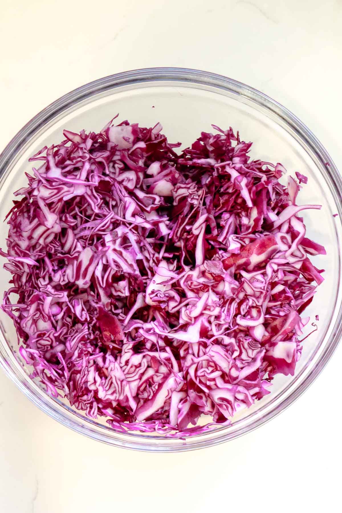shredded red cabbage in a large glass bowl