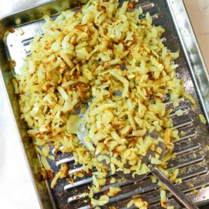 cooking perfectly crispy shredded hash browns in air fryer on stainless steel cooking tray.