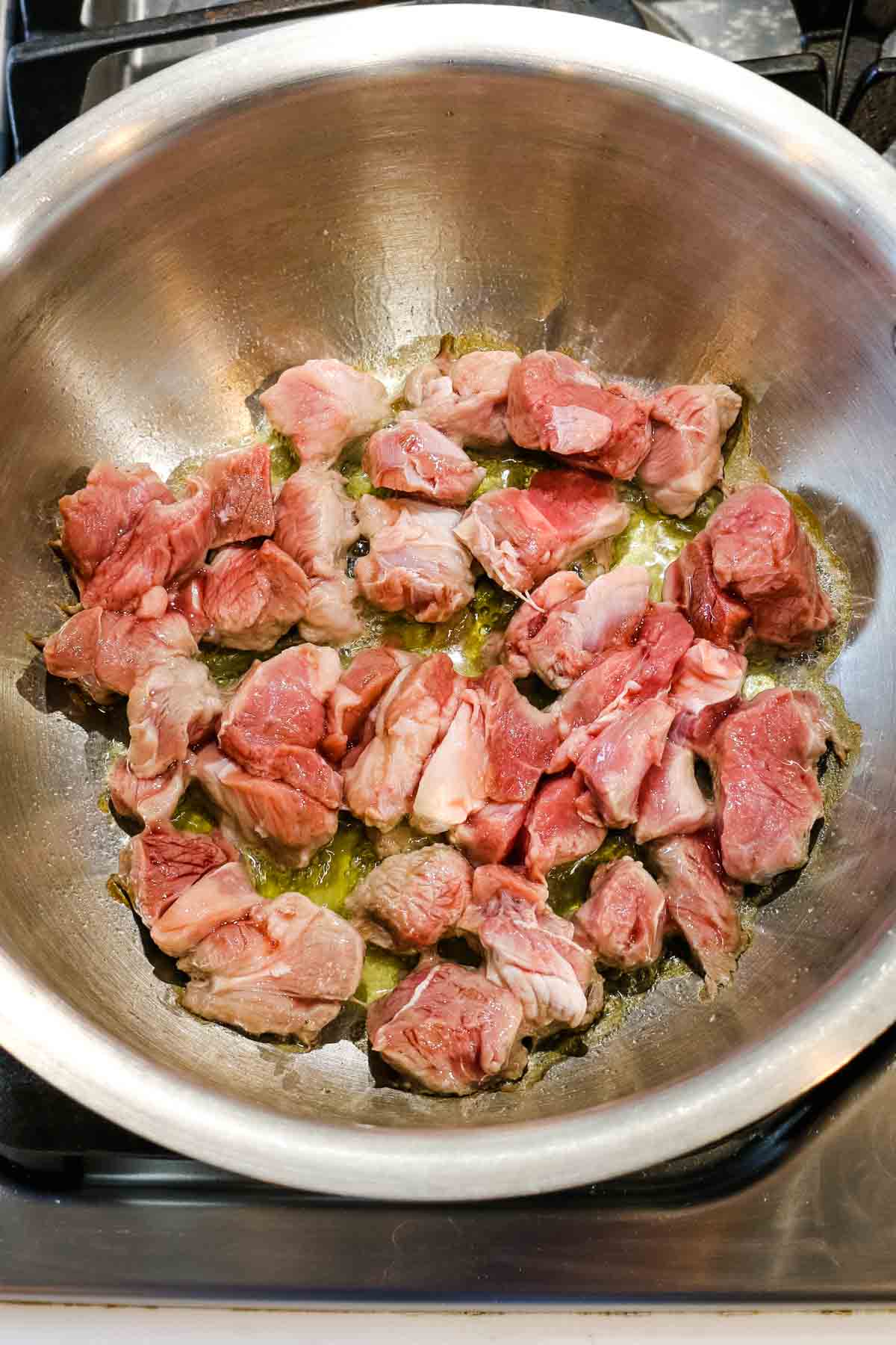 lamb meat browned in a stainless steel pot for shurpa soup recipe.
