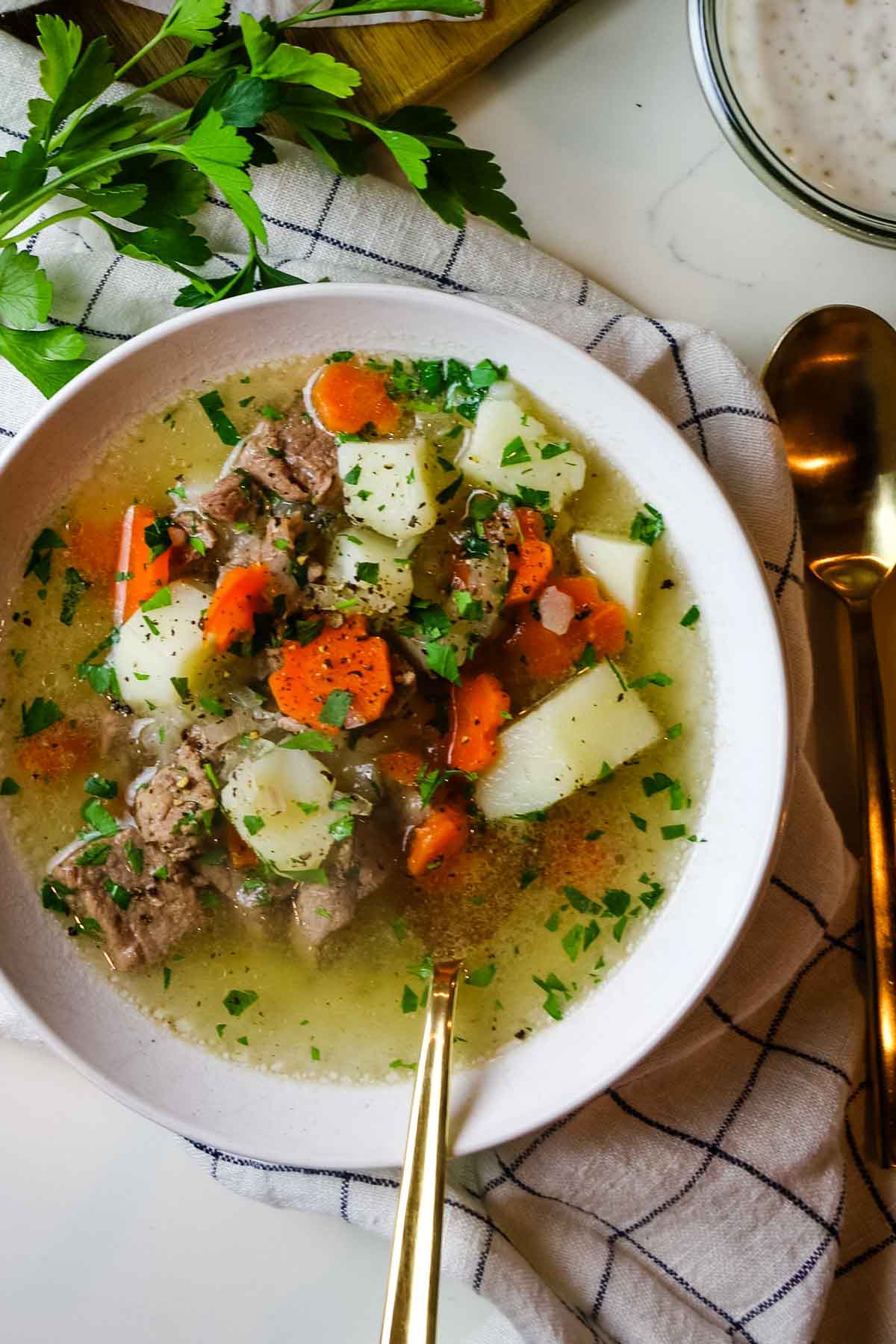 lamb shurpa soup with potatoes and carrots and vegetables in white bowl.