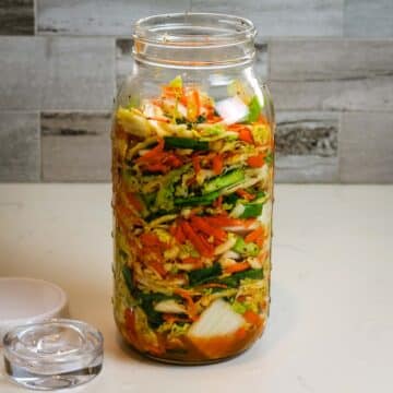 kimchi in half-gallon mason jar with lid on the side in how to make kimchi tutorial.