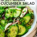 Asian cucumber salad with red onions in a white bowl with text overlay that says 'Spicy Asian Cucumber Salad'