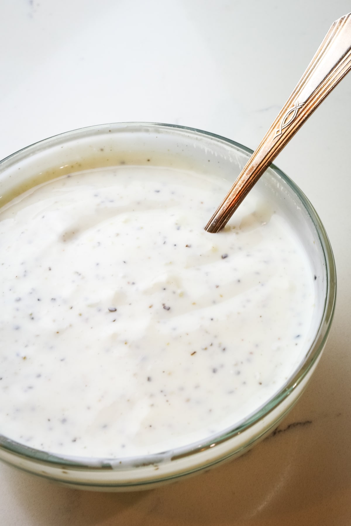 yogurt sauce in clear ramekin with spoon out.