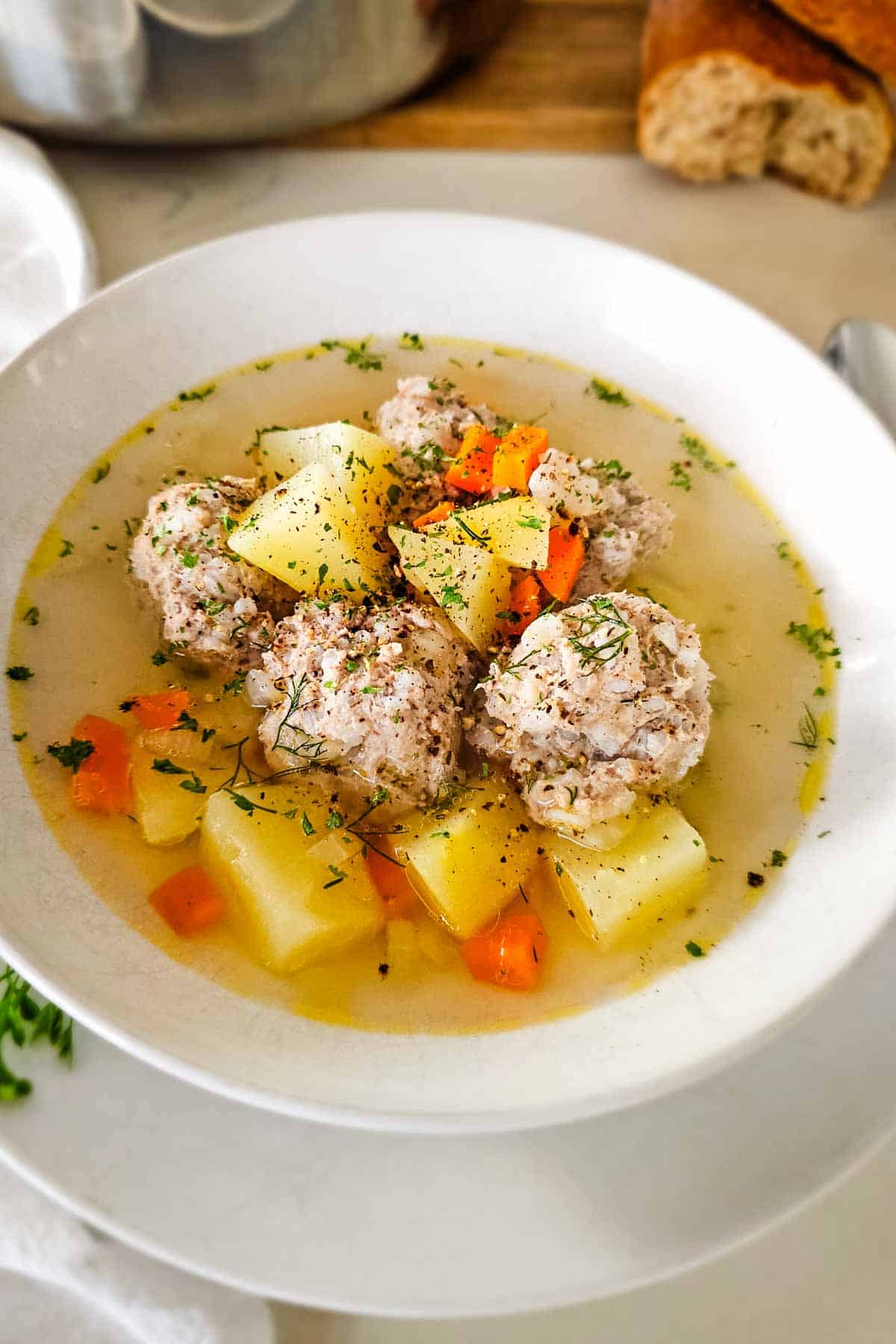 porcupine soup with chicken, potatoes, and carrots in white bowl.