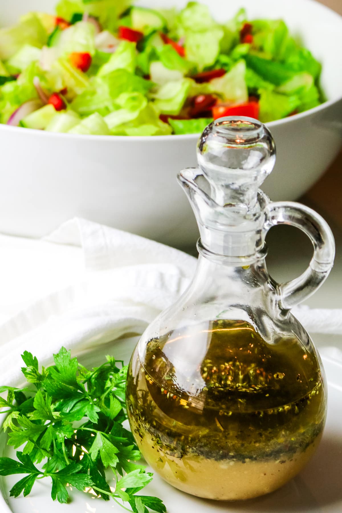 salad dressing with fresh green salad in the background and fresh parsley to the side.