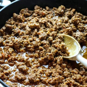 ground beef for tacos in a cast iron skillet with a wooden spoon.
