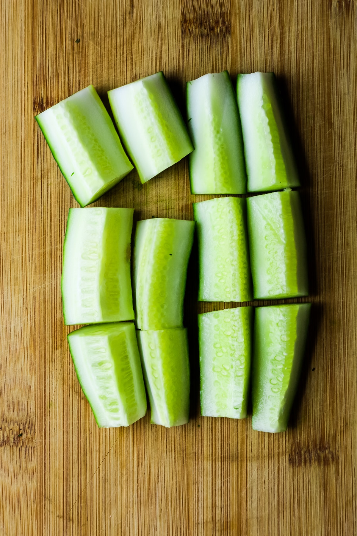 cut cucumbers lengthwise on a wooden cutting board.