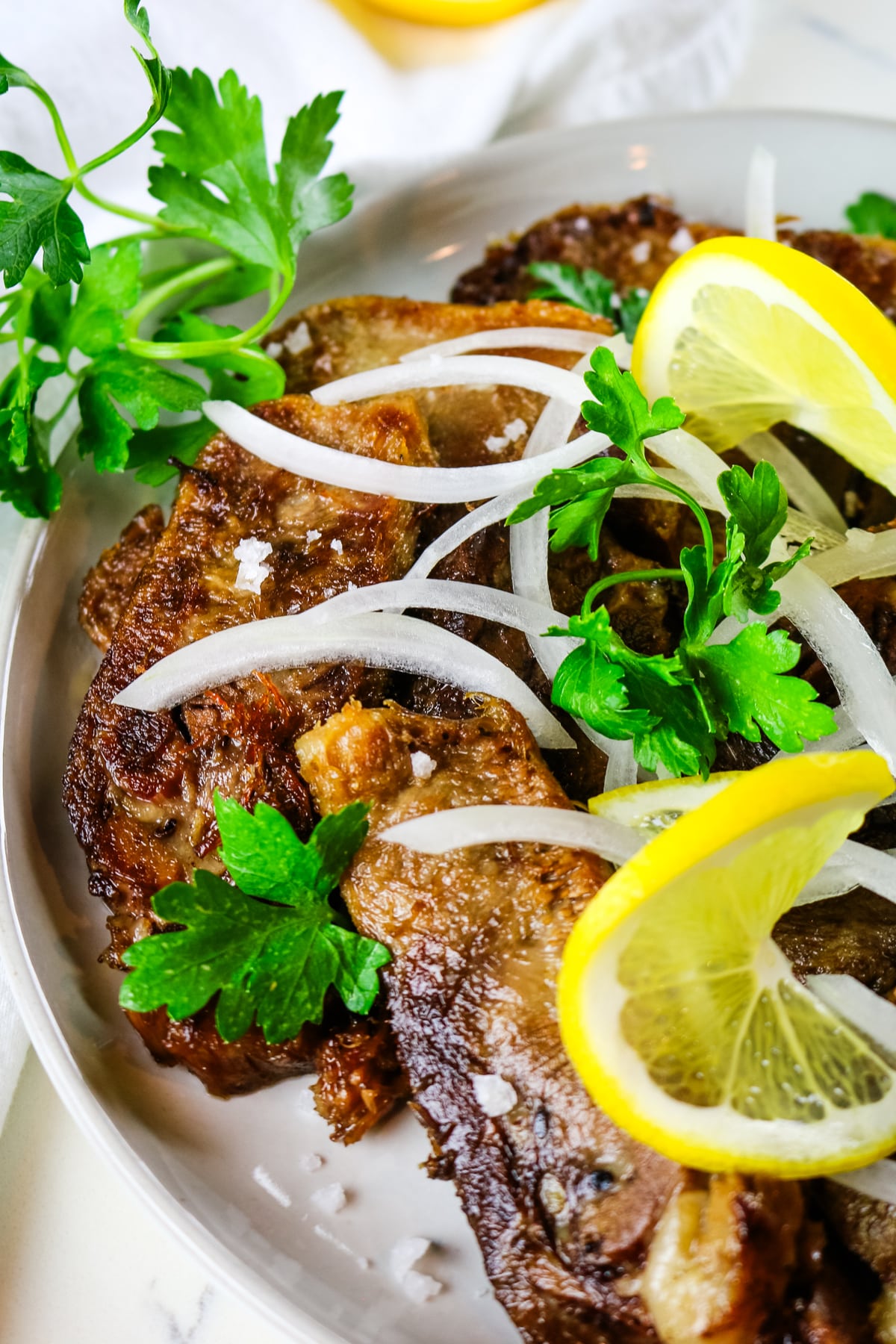 overhead of fried beef tongue with onion and lemon.