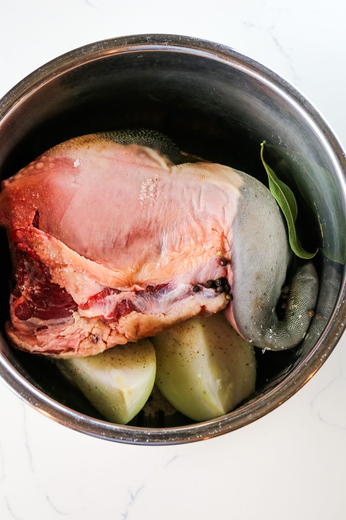beef tongue, onions, and bay leaves in a medium stainless steel pot.