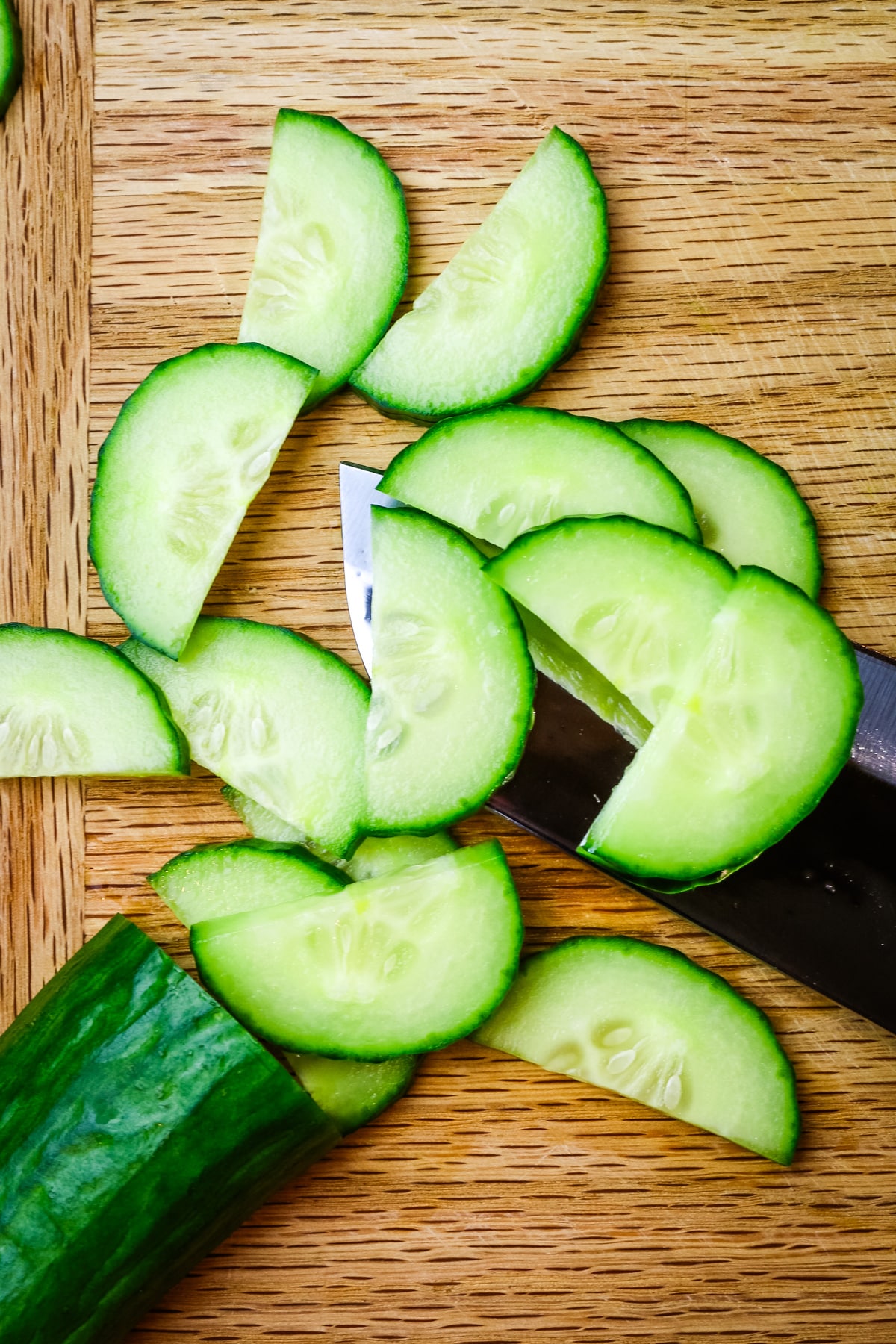 cucumber sliced into half-moons on cutting board.