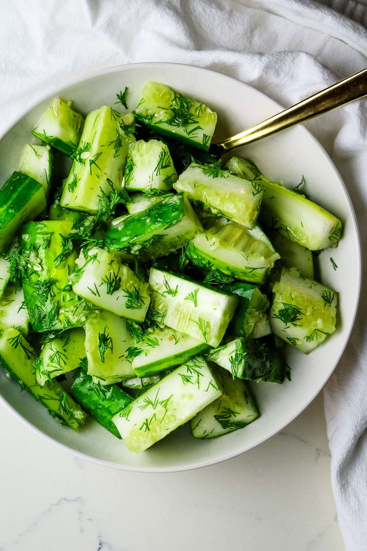 Cucumbers cut up into bite size pieces in a white bowl.