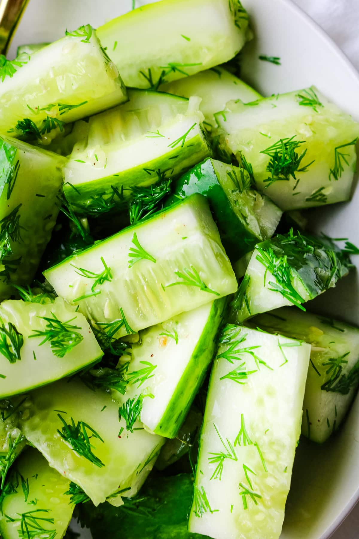 closeup of cut up cucumbers with dill and garlic.