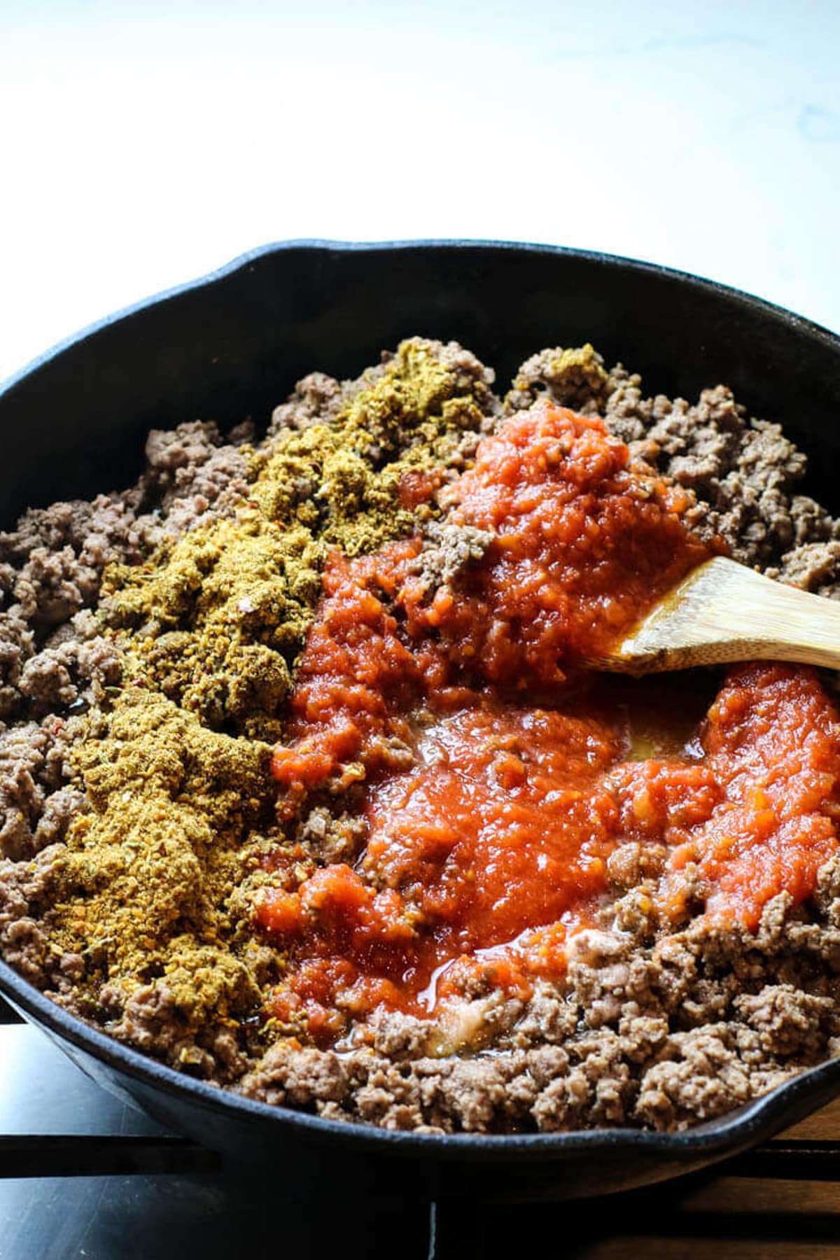 ground beef in a skillet with taco seasoning and tomato sauce added to it.