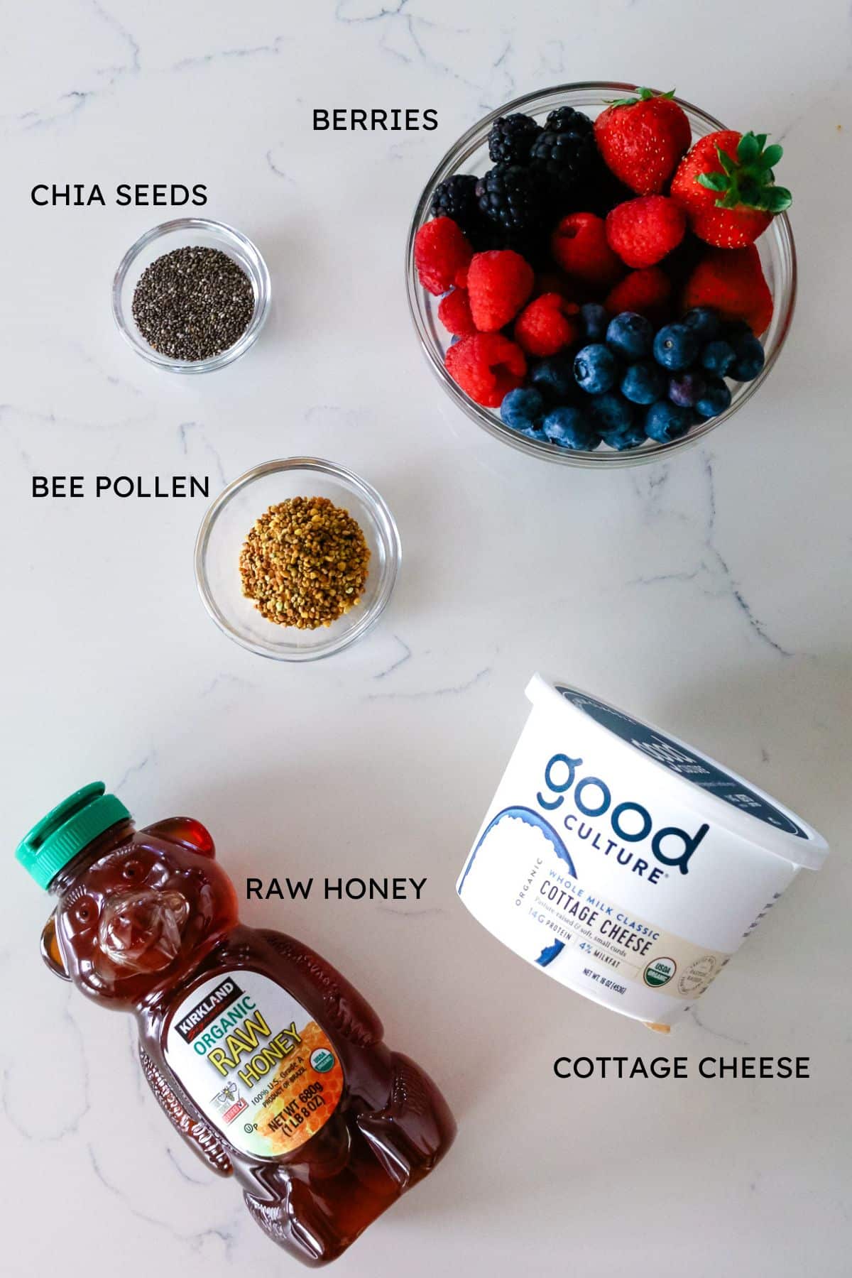 ingredients for cottage cheese bowls include bowl of fresh mixed berries, chia seeds, bee pollen, honey, and one tub of good culture cottage cheese.